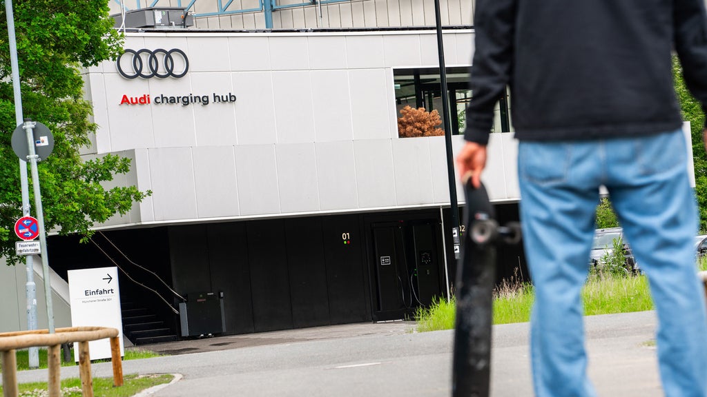 A man stands in front of the Audi charging hub with a skateboard in his hand