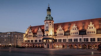 Altes Rathaus Leipzig mit Uhrturm, beleuchtet in der Abenddämmerung auf dem Marktplatz.
