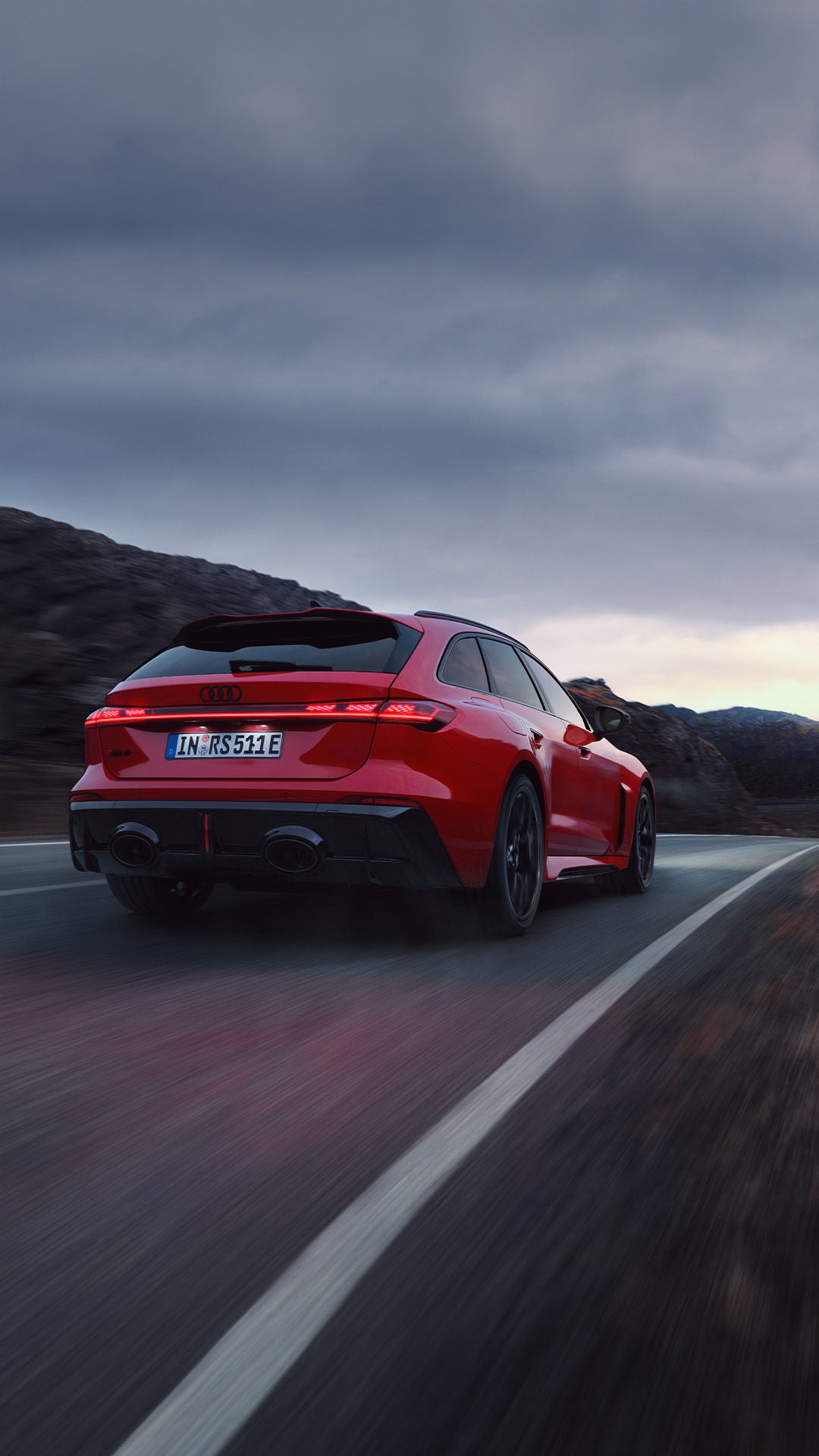 Ein dunkelroter Audi RS5 Avant auf einer einsamen Landstraße in vulkanisch karger Landschaft.