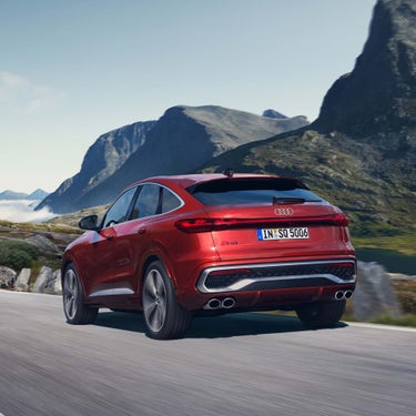Ein roter Audi SQ5 Sportback von hinten in Fahrt auf Bergstraße, umgeben von Felsformationen.