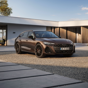 Beige Audi parked beside a modern, minimalist building with stone walls and vertical window panels. A charging station is visible nearby.