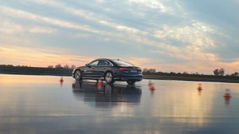 Black A8 50 TDI quattro on a wet track with course, dusk in the background.