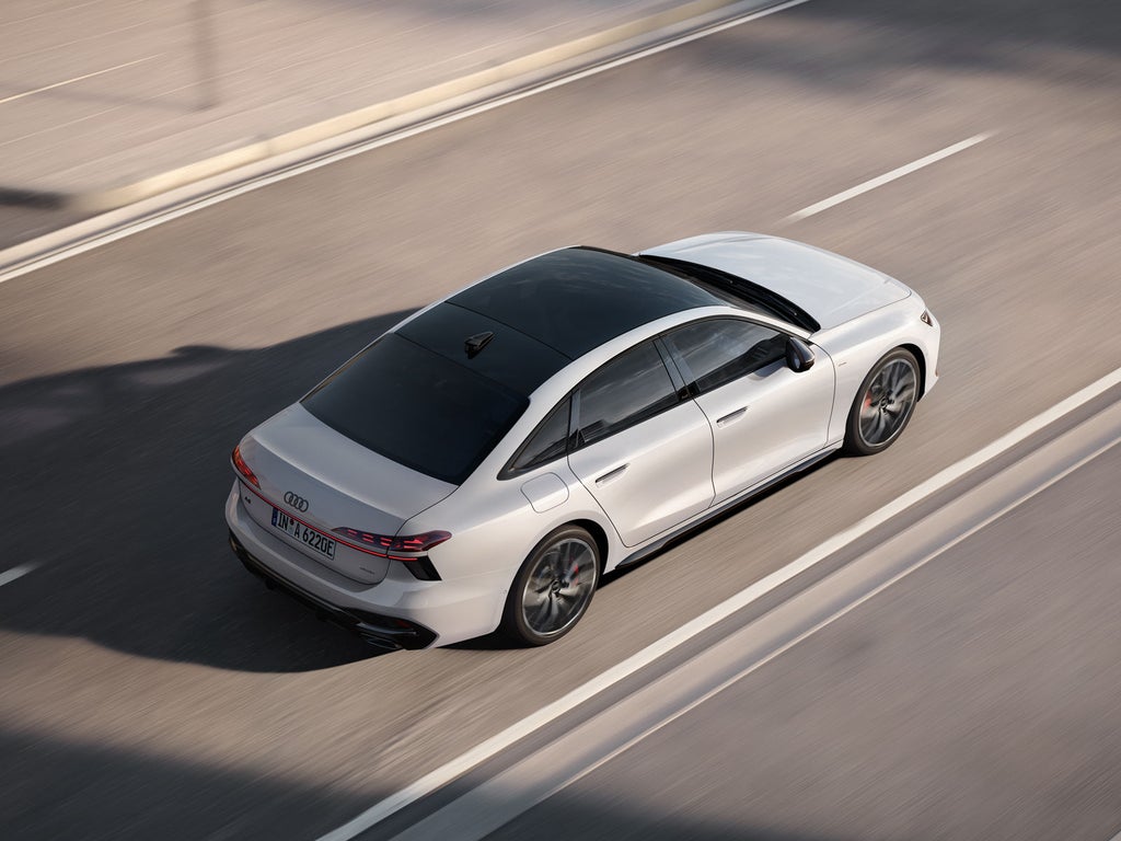 Die weiße A6 Limousine e-hybrid von schräg oben fährt auf einer Straße in urbaner Umgebung.