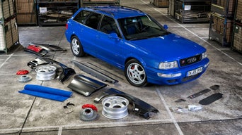 Ein blau lackiertes Audi Modell steht in einer Werkstatt neben Ersatzteilen