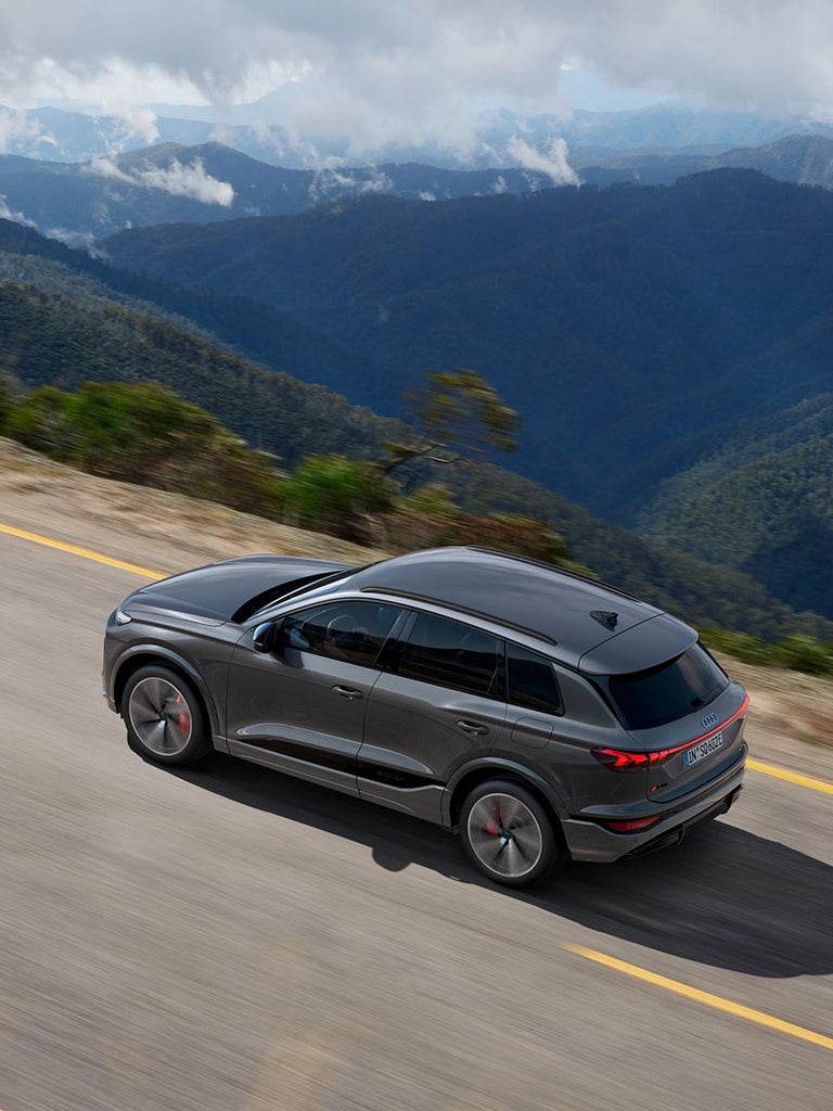 Grauer Audi SQ6 SUV e-tron aus schräger Vogelperspektive auf Gebirgsstraße mit Tal im Hintergrund.