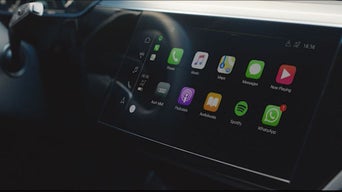 Nahaufnahme eines Touchscreens im Audi mit geöffneter Smartphone-Schnittstelle, Apps wie Telefon, Musik und Karten sichtbar.