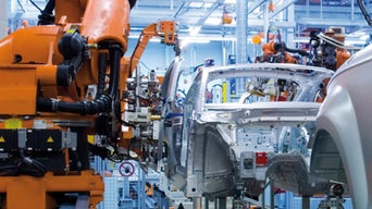 Industrieroboter montieren die Karosserie eines Autos in einer automatisierten Produktionshalle.