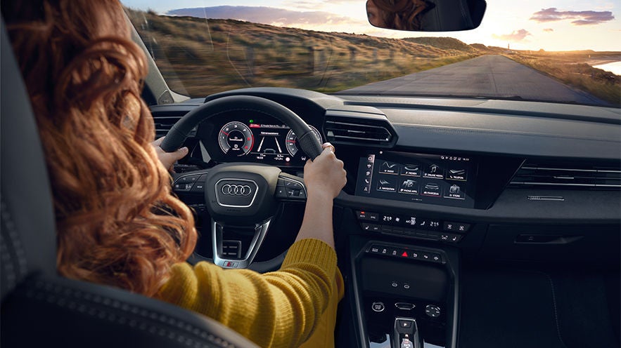 Eine rothaarige Frau fährt einen Audi A3. Die Aufnahme zeigt das Wageninnere. 