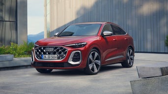 A red Audi SUV parked in front of a modern building.