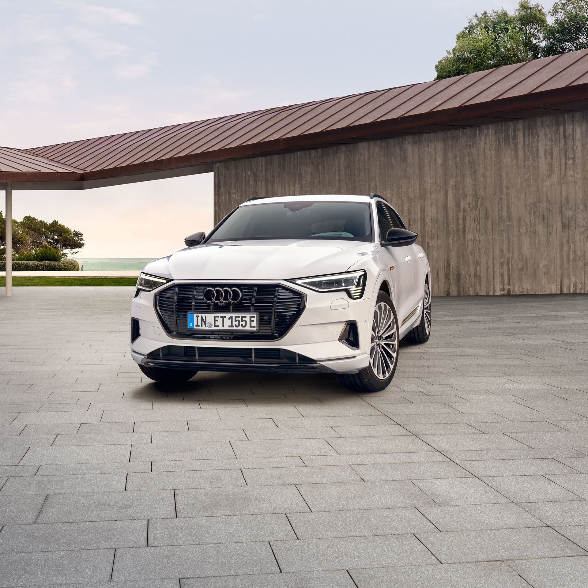 Frontansicht eines weißen Audis vor einer modernen Garage.