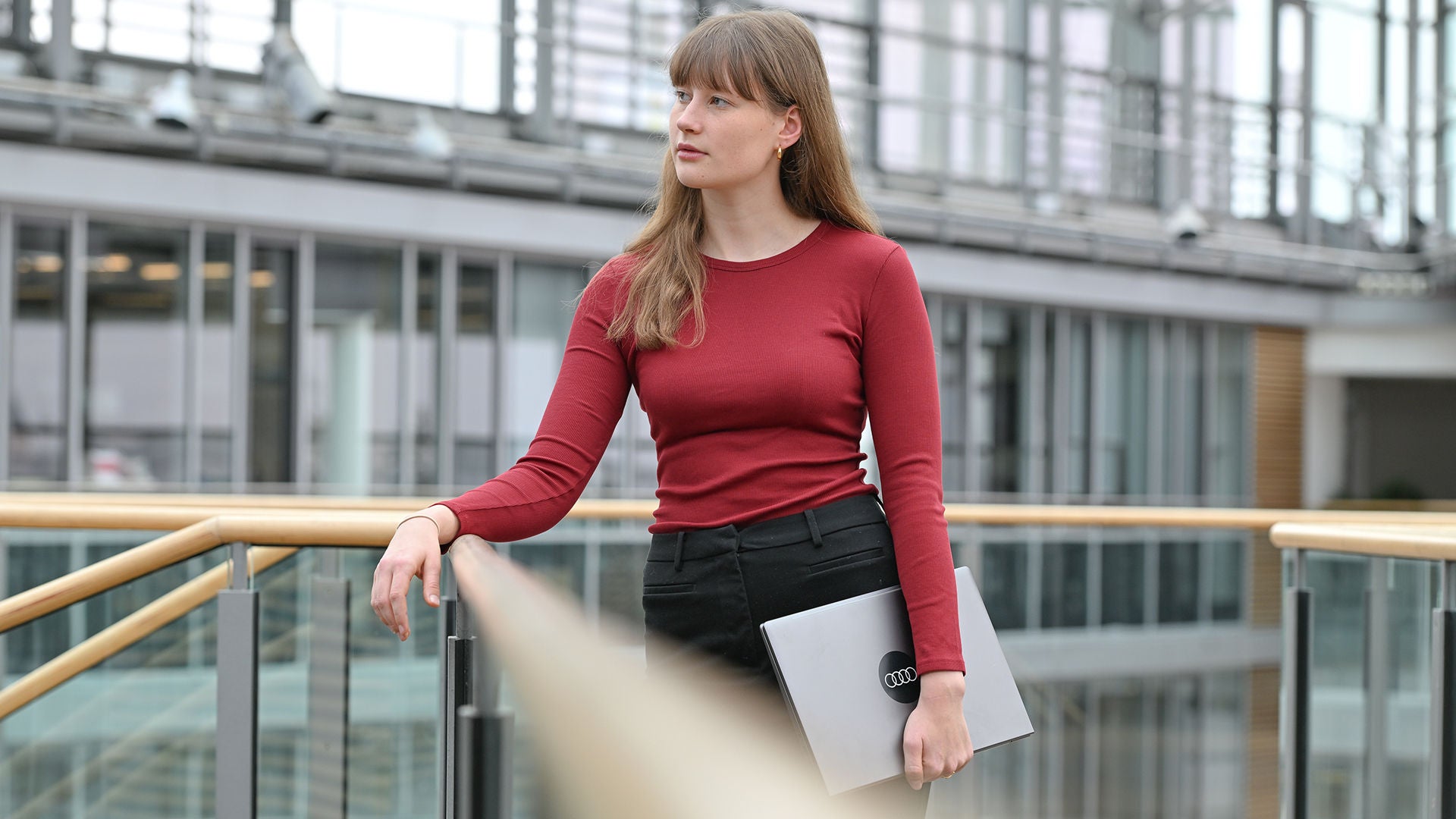 Mädchen ist an ein Geländer gelehnt und steht im Forum eines Gebäudes
