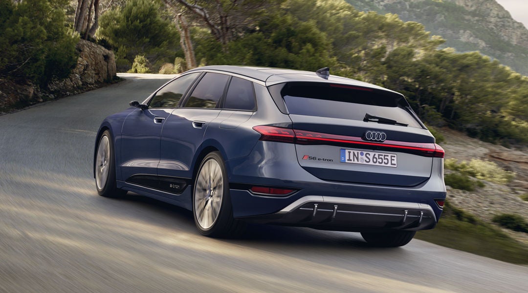 Der S6 Avant e-tron aus schräger Heckansicht fährt durch kurvige Straßen mitten in der Natur. Im Hintergrund sind Bäume und Berge zu sehen.