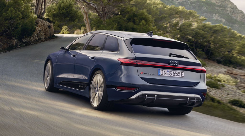 Der S6 Avant e-tron aus schräger Heckansicht fährt durch kurvige Straßen mitten in der Natur. Im Hintergrund sind Bäume und Berge zu sehen.