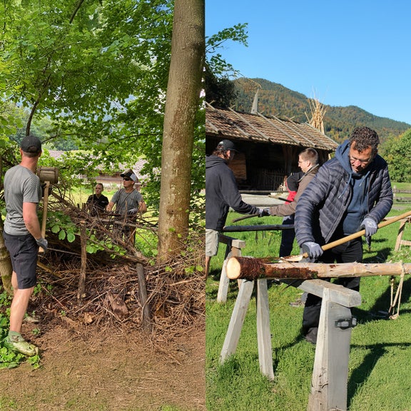 Helfer bauen einen Zaun aus Baumstämmen
