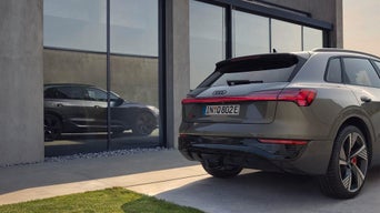 Audi e-tron Heckansicht vor Glasfassade mit Spiegelung.