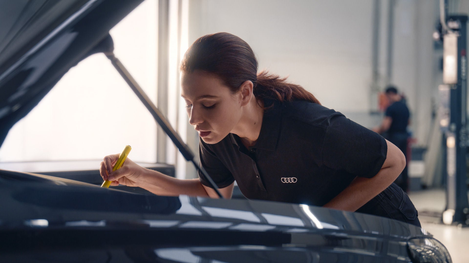 Audi Mitarbeiterin überprüft offene Motorhaube.