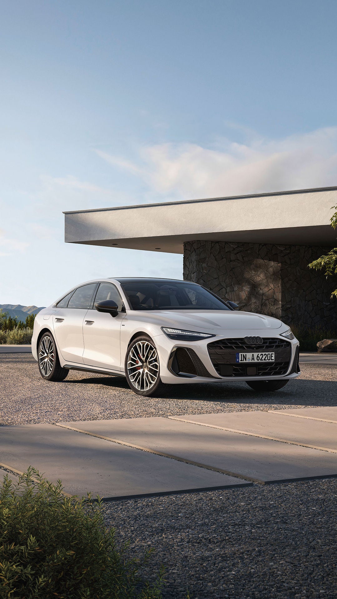 A white Audi A6 Saloon e-hybrid parked outdoors, showcasing its modern design and sporty features against a scenic backdrop.