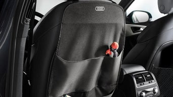 Schwarzer Rücksitzschutz mit Audi-Logo und Tasche für Spielzeug.