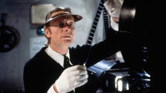 Ein Filmvorführer steht neben einem alten Filmprojektor und überprüft ein Stück Film.