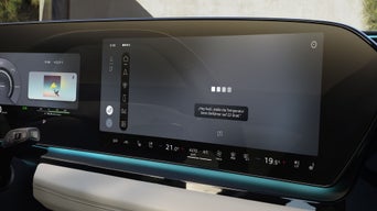 Zentrales Infotainment-Display in einem Audi zeigt Sprachausgabe-Einstellungen und Musik-Player.