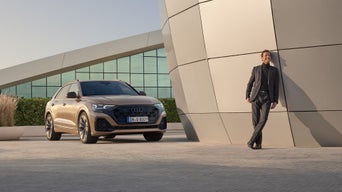 SUV Audi Q8 debout à côté d’un bâtiment avec une personne