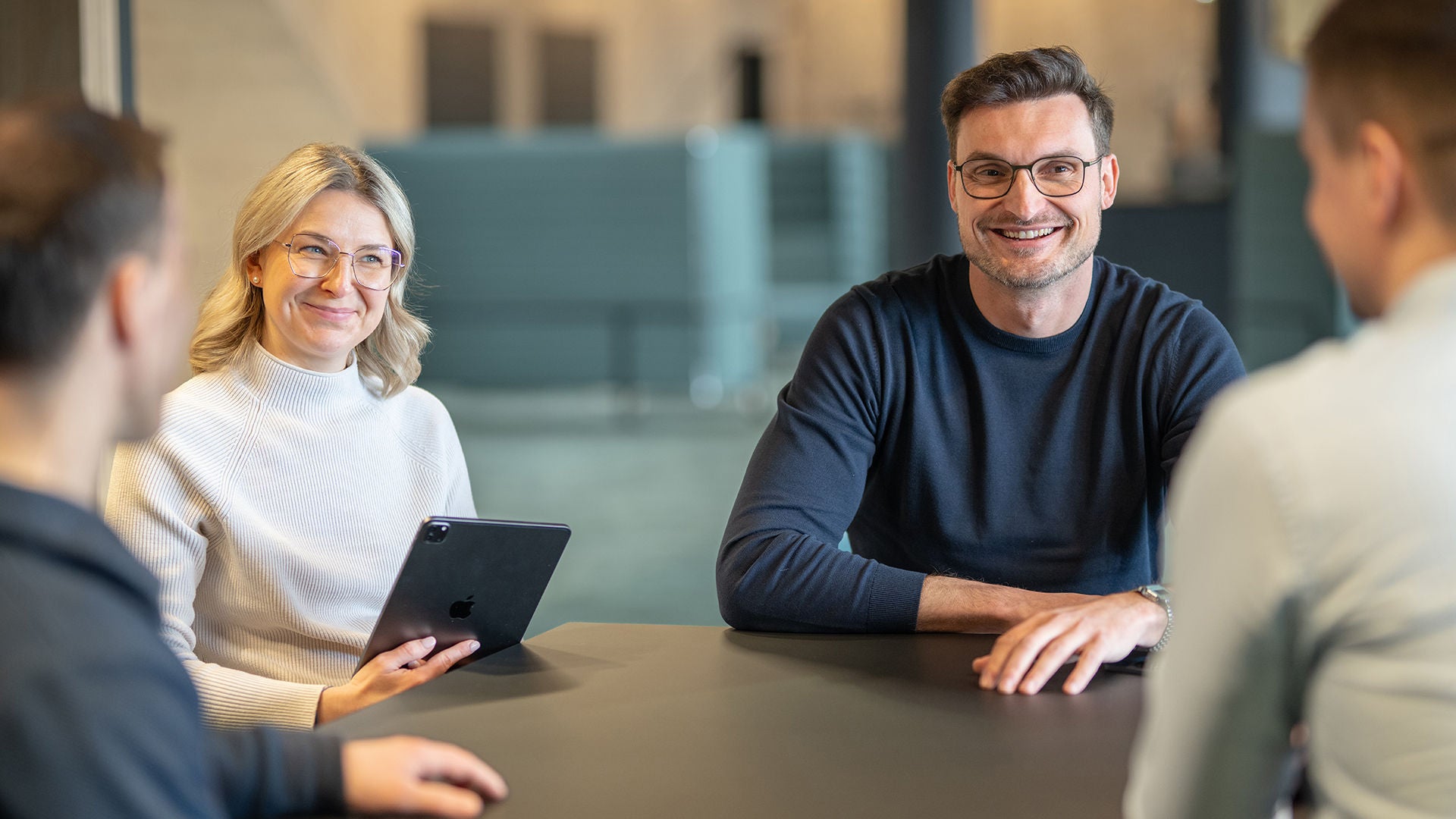 Alexander Lang is sitting at a table with three colleagues and smiling
