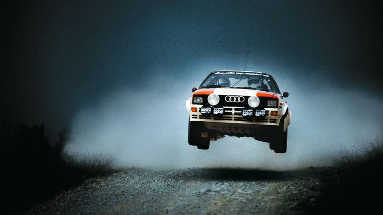 An old Audi drives through dusty terrain