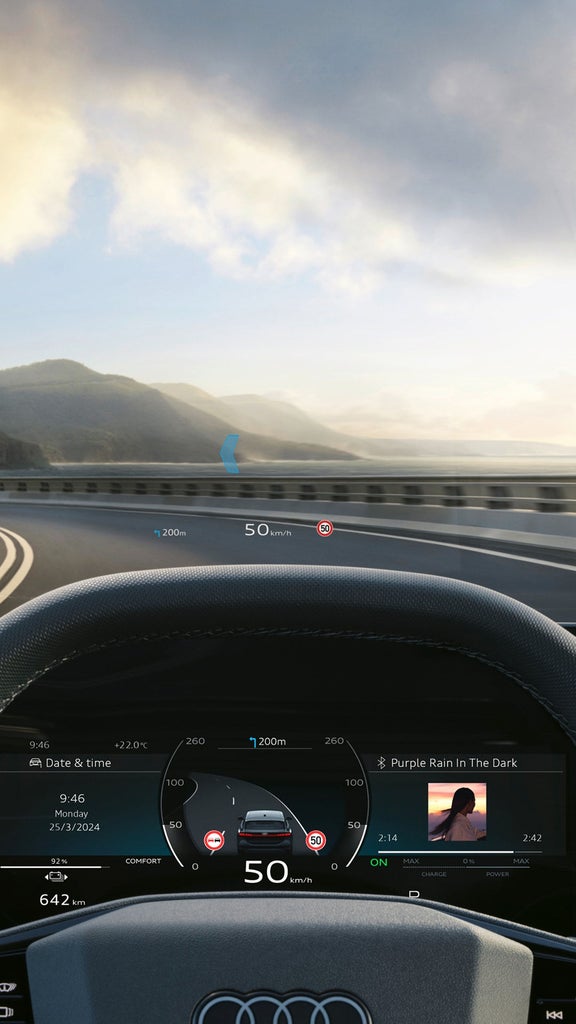 Driver's view inside an Audi vehicle with hands on the steering wheel and digital displays