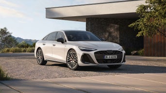 White A6 Saloon e-hybrid parked in front of modern house with a small tree