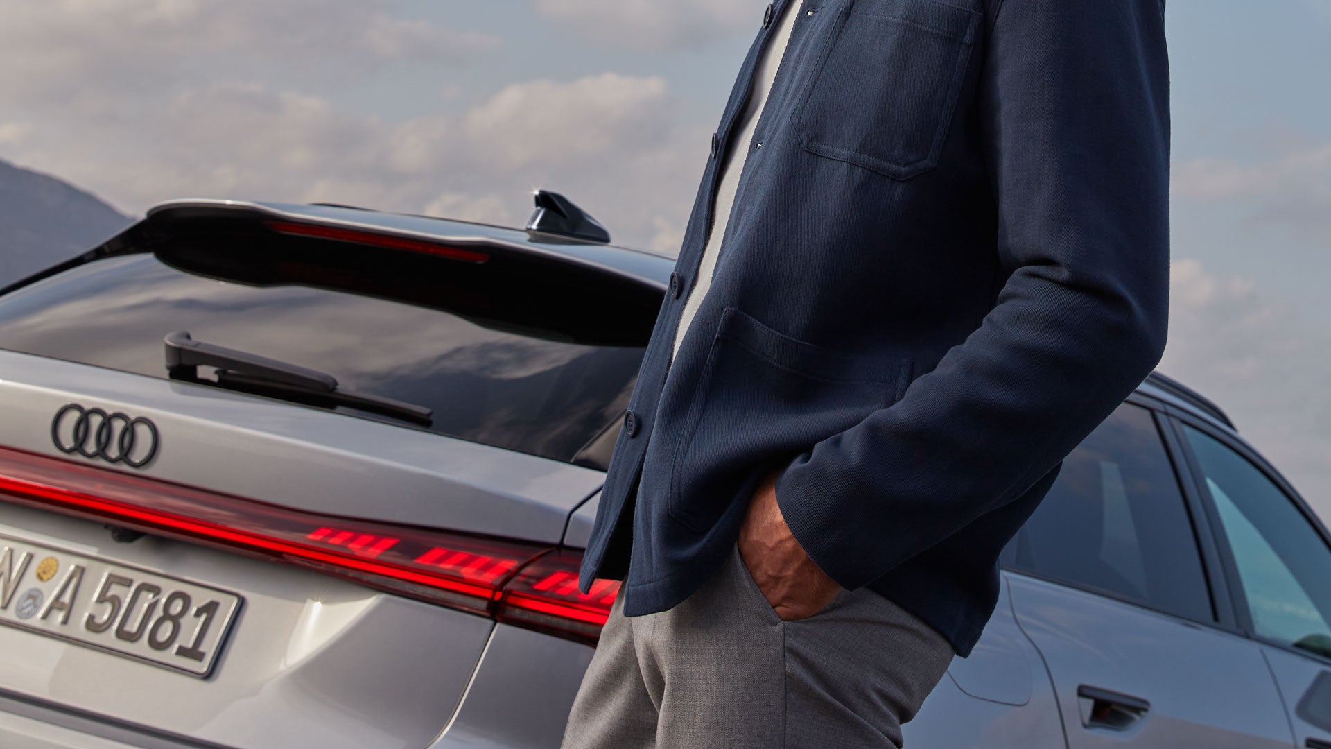 Oberkörper eines Mannes vor einem grauen Audi