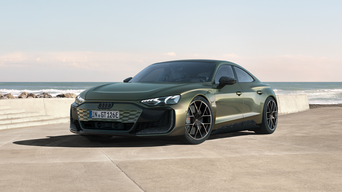 Green Audi RS e-tron FT performance on concrete, facing left, with sea and blue sky in background.