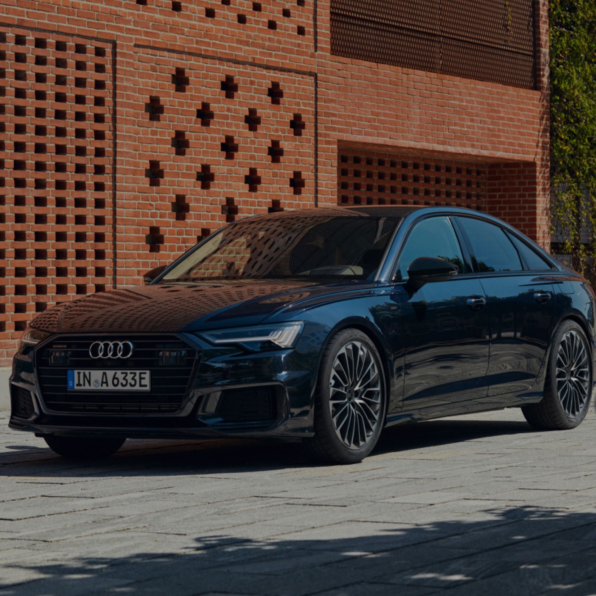 A sedan parked in front of a brick building.