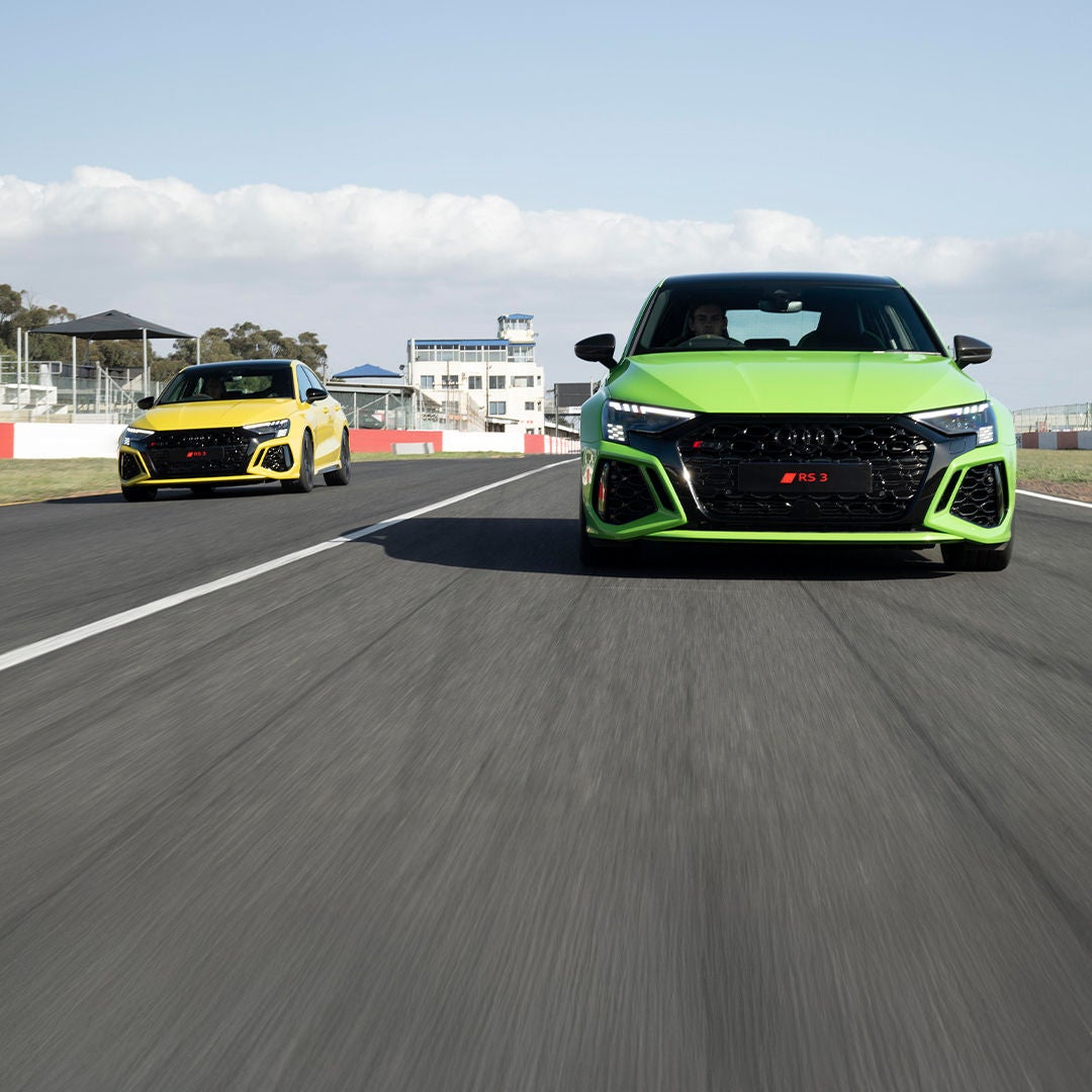 Two Audi cars facing each other side by side with beautiful sky at the back