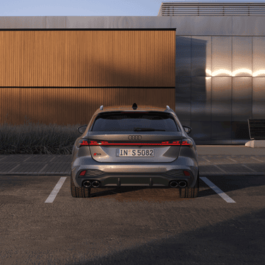 A silver Audi S5 Avant parked outdoors near a modern building at dusk.