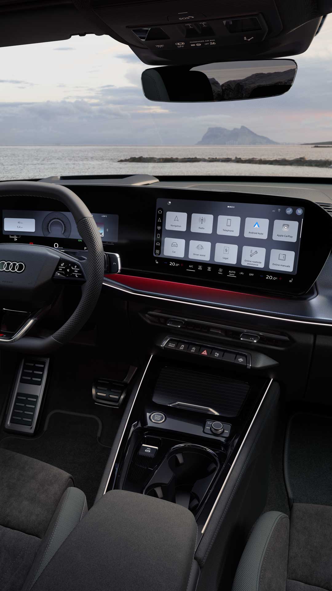 Rear view of the cockpit of the Q3 Sportback with steering wheel, panoramic display, and red ambient lighting package. The sea can be seen through the windshield.