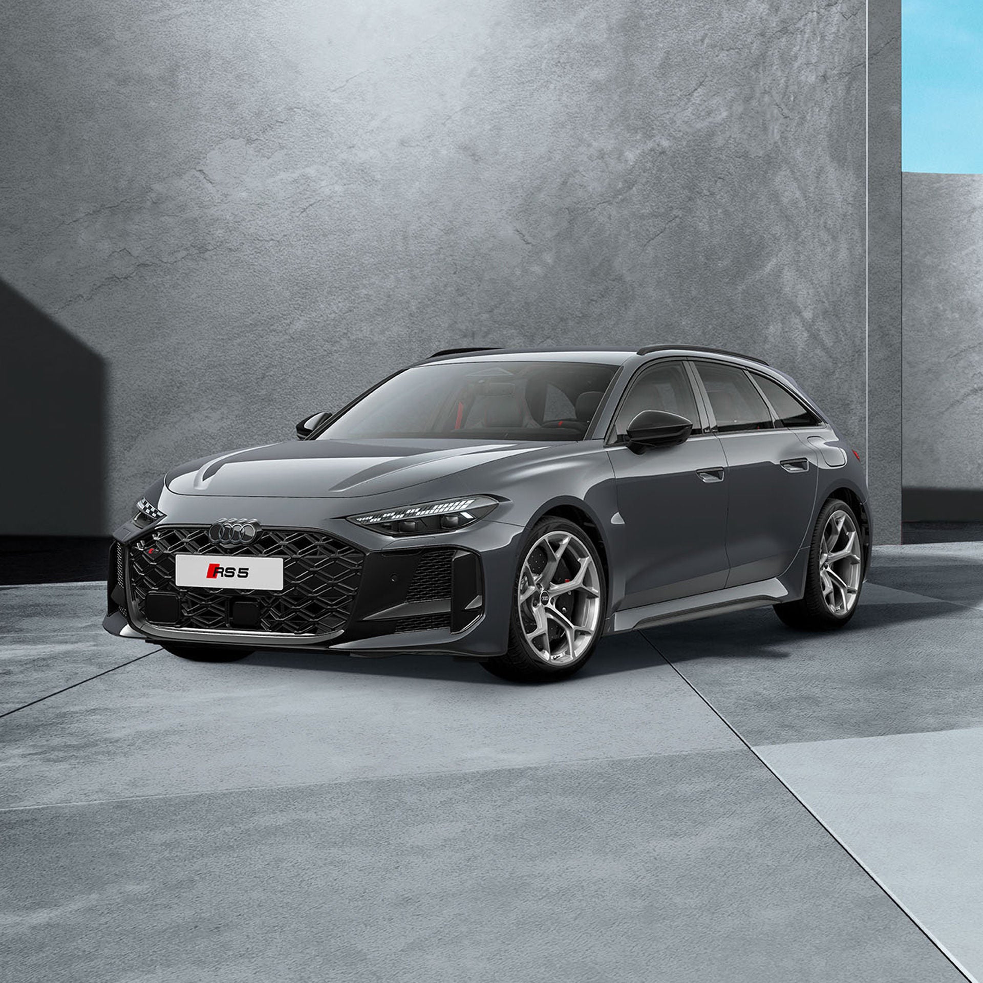 Ein dunkelgrauer Audi RS 5 Avant von schräg vorne fotografiert vor einer modernen Kulisse.