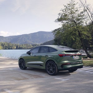 De Q4 Sportback e-tron staat op een parkeerplaats aan een water.