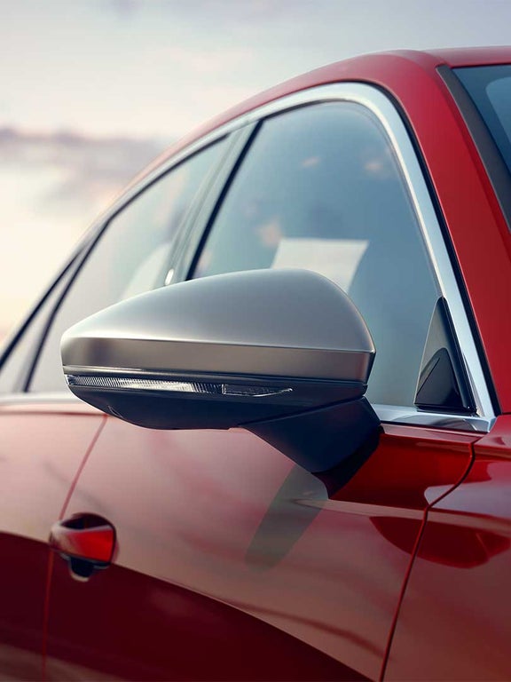 Nahaufnahme eines silbernen Außenspiegels an einer roten Audi S6 Limousine TDI mit integrierter Blinkleuchte.