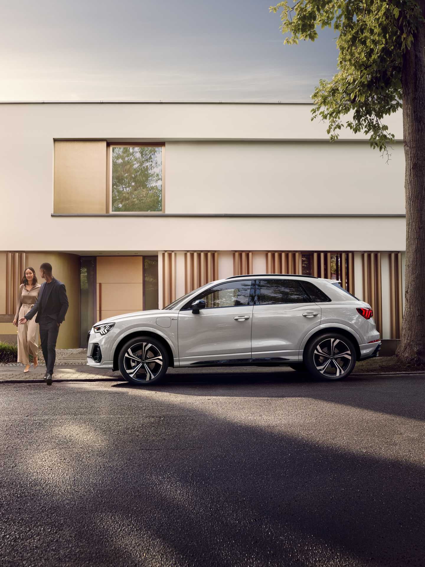Man escorting lady to across the road in front of white Audi TFSI e.
