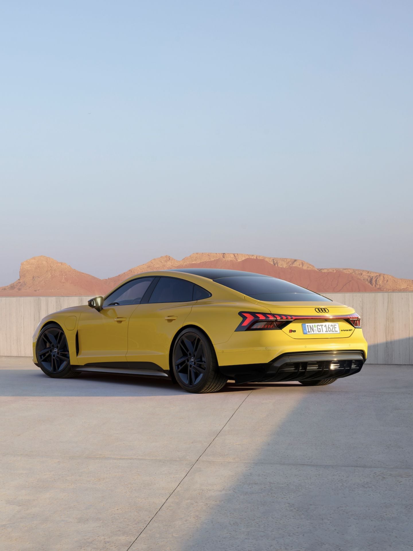 Yellow Audi car parked with desert hills in the background.