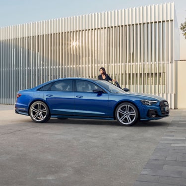side view of blue Audi A8 S8 with lady in background near open door