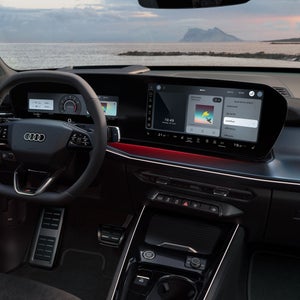 Visuale dal posto di guida con volante e display panoramico touchscreen che mostra le funzioni integrate.