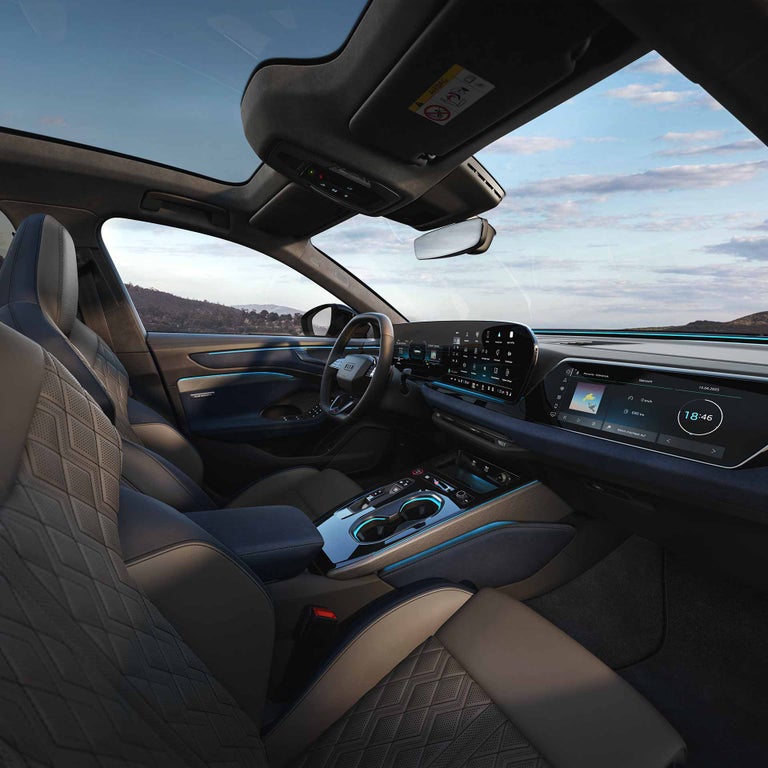 Innenraum einer Audi A6 Limousine mit Sportsitzen, großem Display und Ambiente-Beleuchtung bei Sonnenuntergang.