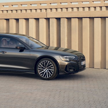 Sedan parked near a concrete wall, showcasing shiny rims and elegant design.