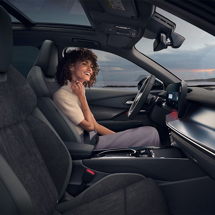 Une femme souriante est assise sur le siège conducteur d'un Audi Q3.