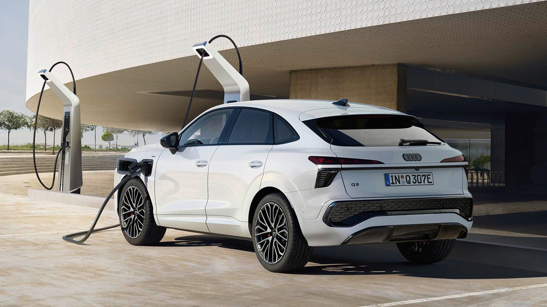 Ein weißer Q3 Sportback e-hybrid ist an einer Ladesäule angeschlossen