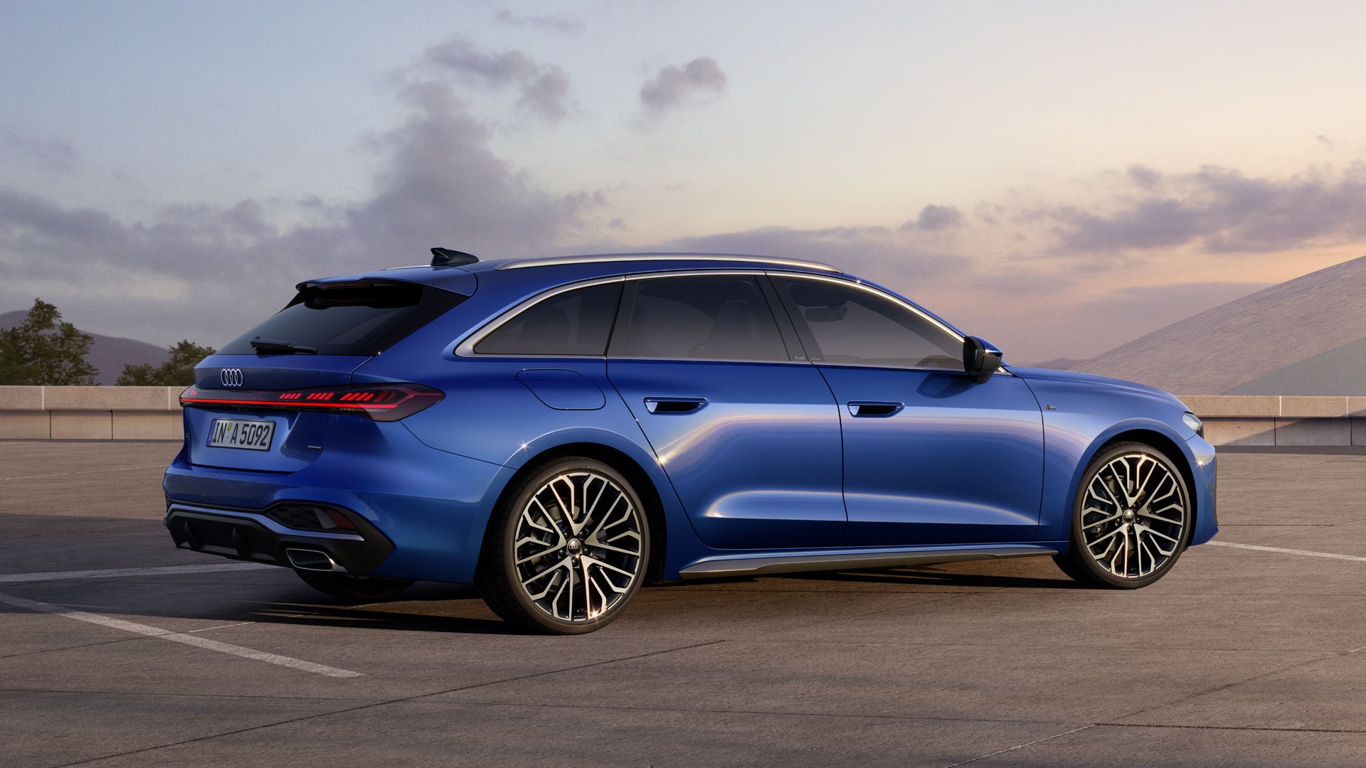 Der A5 Avant in Sepangblau Perleffekt steht im schrägen Seitenprofil auf einem großen Parkplatz.