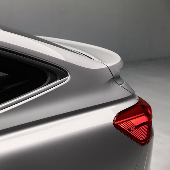 Nahaufnahme eines silbernen Audi Q4 Sportback e-tron Hecks mit leuchtendem Rücklicht und elegantem Dachlinienverlauf.