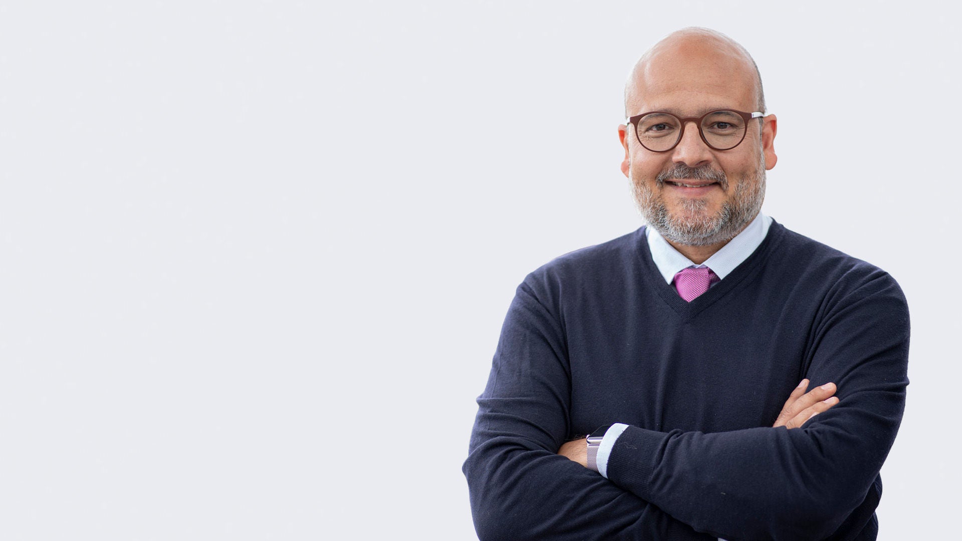 Mann im dunklen Pullover und mit Brille verschränkt die Arme vor der Brust.