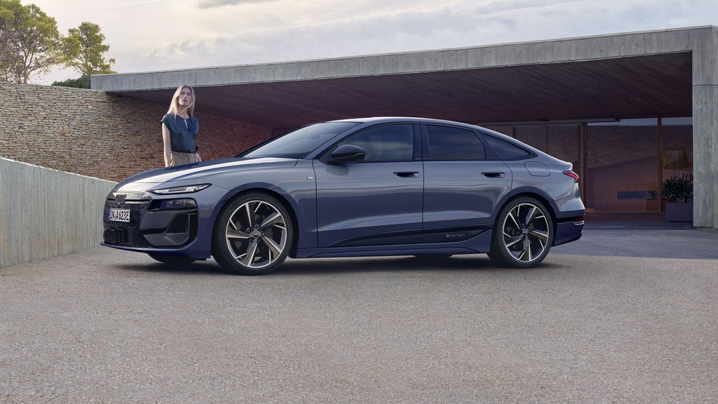 Vrouw staat achter de voorkant van een Audi A6 Sportback e-tron.